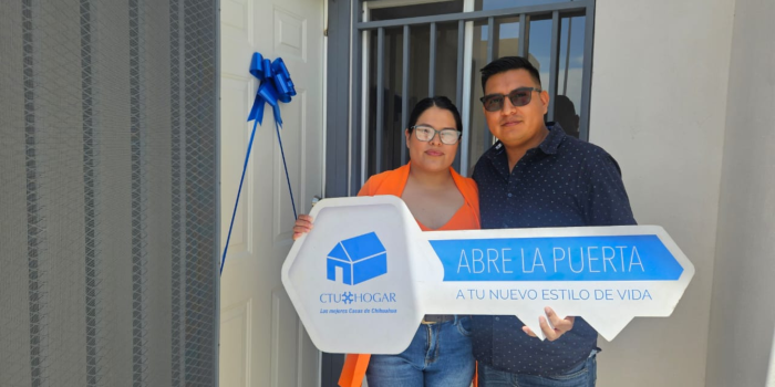 Pareja feliz sosteniendo una llave simbólica frente a su nuevo hogar de CTU Hogar en Chihuahua.